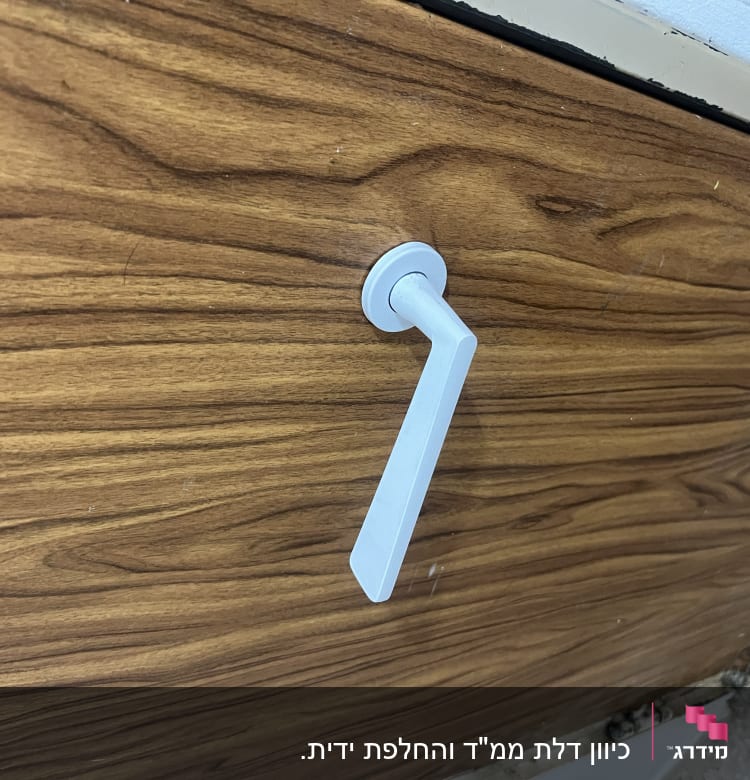 ידית דלת לבנה על דלת עץ